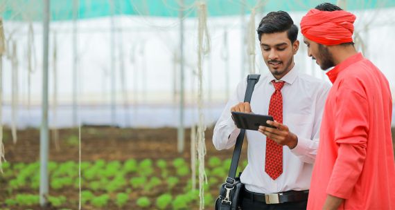 Young Indian agronomist and farmer discussing technological solutions